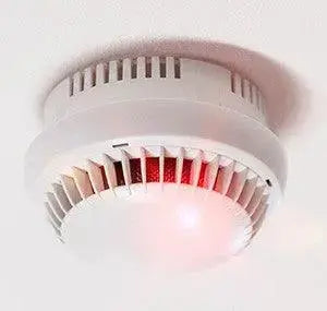 Détecteur de fumée blanc au plafond avec voyant lumineux rouge, sécurité incendie